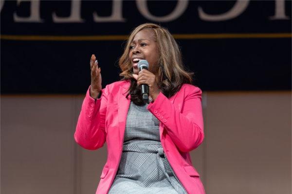 LaTosha Brown in pink jacket speaks with a microphone in her right hand